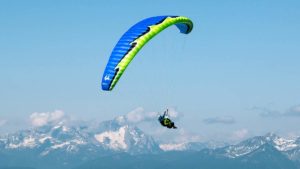 Das Bild zeigt den Tandem Gleitschirm U-Turn Asterion LT. Es ist ein leichter Tandemschirm und eignet sich für den Passagierflug. Das Bild zeigt die Farbe blau-grün. Der Schirm befindet sich im Flug mit Passagier.